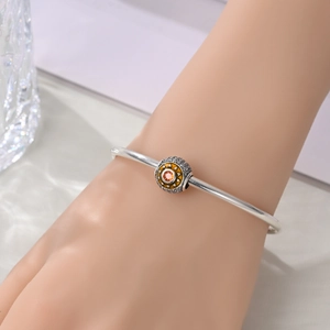 Detailed shot of a silver charm bracelet with a sun motif bead and orange gemstone