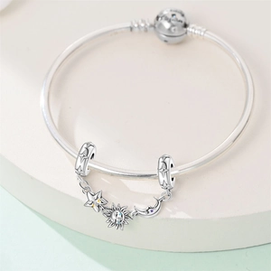 Dettaglio del bracciale con ciondoli sole e luna e catena di sicurezza con motivi celesti