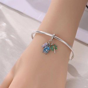 Close-up of silver travel themed charm bracelet with palm tree and suitcase charms