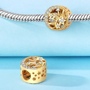 Detalle de un dije celestial chapado en oro con motivos de estrellas y piedras circón