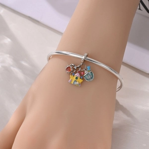 Detail of silver bangle featuring colorful crab, castle, and sand bucket enamel charms