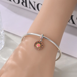 Detailed close-up of a silver charm bracelet with a sun pendant and orange zircons