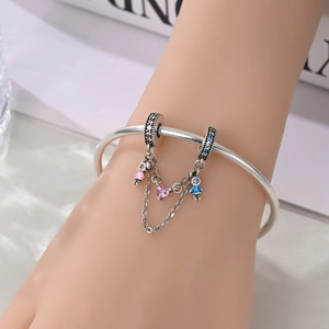 Dettaglio catena di sicurezza con ciondoli bimbo, bimba e cuore rosa su bracciale