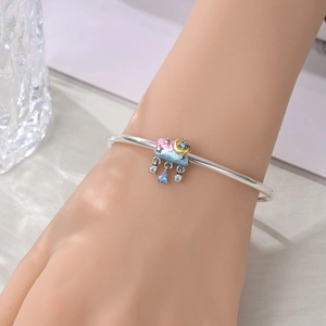 Detail of silver bangle with moon and cloud charm featuring blue teardrop gemstone