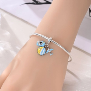 Close-up of a silver charm bracelet with blue camera, airplane, and sun wave pendants