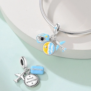 Detail of summer travel charms with blue camera, suitcase and sun wave pendants