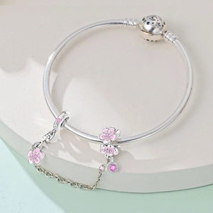 Dettaglio di ciondoli in smalto rosa a forma di ciliegio con catena di sicurezza argento