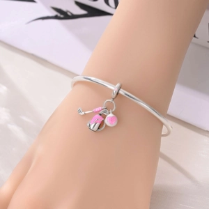 Detail of silver bangle featuring pink enamel golf club bag and heart charms on a wrist