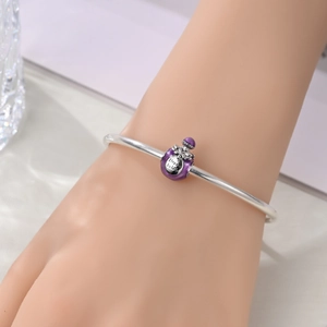 Silver bangle with a purple enamel perfume bottle charm engraved with Dream Boldly