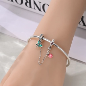 Dettaglio del bracciale d'argento con farfalla in smalto verde e ciondoli a fiore rosa