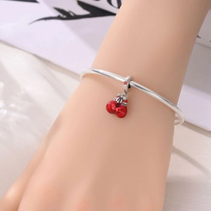 Detail of silver bangle with red enamel boxing glove charm worn on wrist for summer