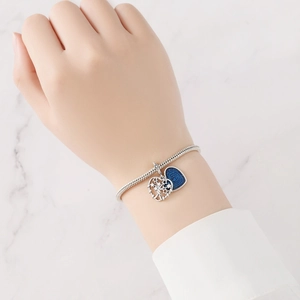 Detalle de pulsera de cadena de serpiente plateada con dijes de corazón azul y estrella