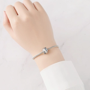 Primer plano de pulsera de plata con dijes de estrellas de circonita azul en la muñeca