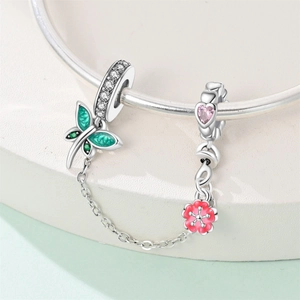 Dettaglio della catena di sicurezza con pendente a farfalla e cuore rosa sul bracciale