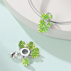 Dettaglio dei ciondoli a fiore in smalto verde su un braccialetto in argento pregiato