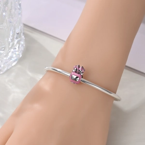 Detailed close-up of a silver charm bracelet with a pink enamel perfume bottle pendant
