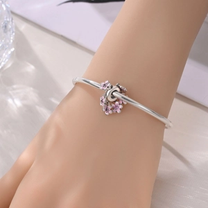 Vista dettagliata di ciondoli a farfalla e fiori rosa su un bracciale in argento