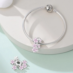 Dettaglio macro dello charm a fiore in argento S925 con smalto rosa su catena a serpente