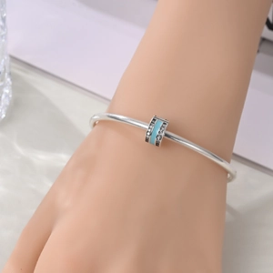 Silver bangle with sky blue enamel charm and pavé zircons on woman's wrist