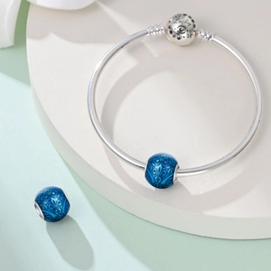 Dettaglio della chiusura del bracciale argentato con incisione Lucky e ciondoli blu