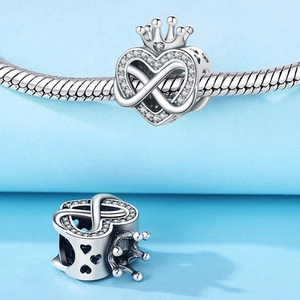 Nahaufnahme von silbernem Herz-Kronen-Charm mit Zirkonia und Unendlichkeitssymbol an Kette