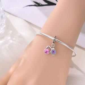 Detail of a silver bracelet with BT21 pink enamel heart lock and purple charm charms