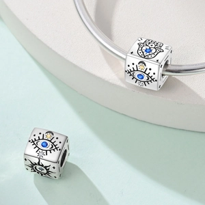 Makro-Detail des Würfel-Charms mit Hamsa-Hand und Evil Eye Motiven in Silberoptik