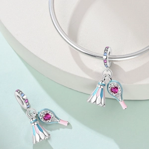 Macro shot of silver sports charm with heart-shaped pink zircon and colorful enamel