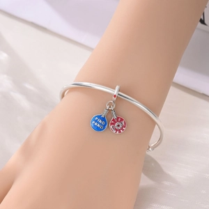 Detail of silver bracelet featuring red and blue ping pong paddle charms with tiny crystals