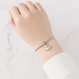 Vue détaillée d'un bracelet maille serpent en argent avec un pendentif éléphant rose au poignet