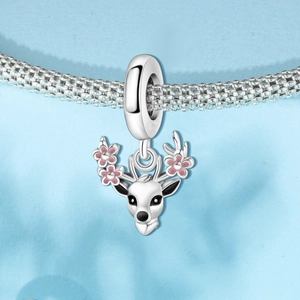 Vue macro d'une breloque renne avec détail floral rose sur un bracelet tressé