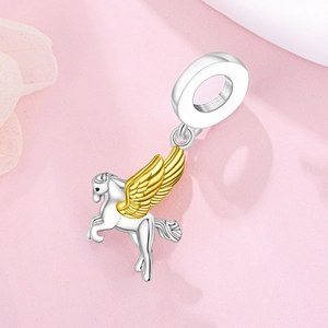 Détail macro du pendentif Pégase en argent avec ailes dorées sur fond rose doux
