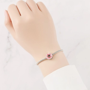 Dettaglio charm in smalto rosa su bracciale a catena serpente argentato per gioielli DIY