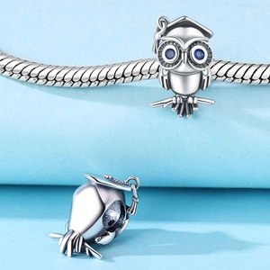 Détail d'une breloque hibou avec chapeau de diplômé et pierres bleues sur chaîne
