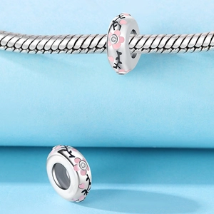 Dettaglio macro del charm ciliegio con petali rosa e zircone su bracciale in argento