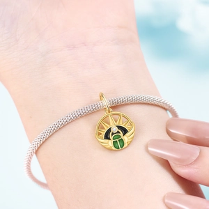 Nahaufnahme des goldenen Skarabäus-Anhängers mit grünem Inlay auf Silberarmband