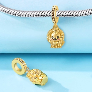 Détail d'une breloque lion dorée avec fard rouge sur un bracelet à maille serpent