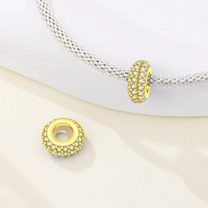 Macro di charm placcati in oro con pavé di zirconi su un bracciale a maglia d'argento