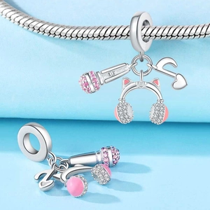 Macro detail of silver musical charms with microphone and cat ear headphones on a chain