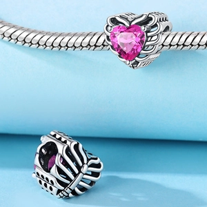 Dettaglio di un charm a cuore con zircone rosa e filigrana d'argento su catena a serpente