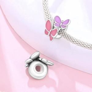Details von silbernen Schmetterlingsperlen mit rosa und lila Emaille für Armbänder