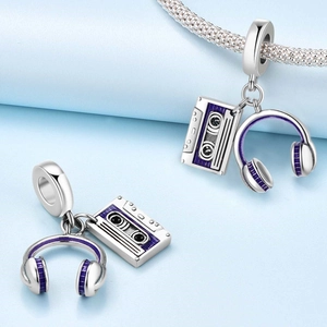 Macro detail of music charms featuring a purple enamel headphone and retro tape dangle