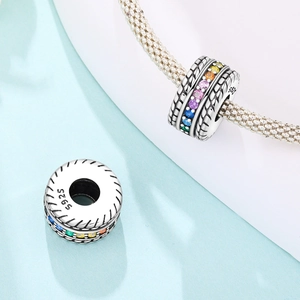 Dettaglio macro dello charm in argento S925 con zirconi arcobaleno e trama a corda su bracciale