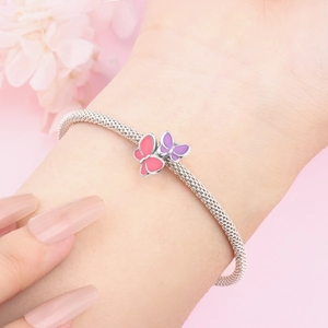 Nahaufnahme eines silbernen Schmetterlingsarmbands mit rosa und lila Emaille-Details