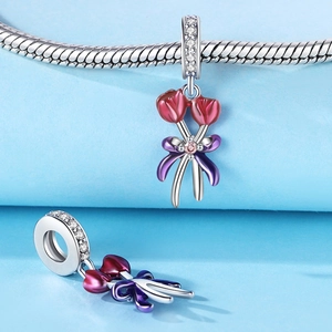 Vista macro de dije de tulipán rojo con lazo púrpura en pulsera de plata