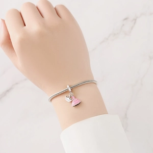 Close-up of a silver charm bracelet with a pink princess dress and crown pendant