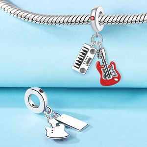 Macro detail of silver music charms featuring a red guitar and keyboard for charm bracelets