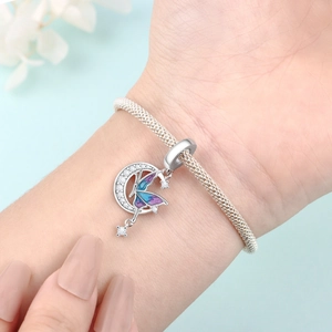 Detailansicht eines silbernen Schmetterlingsanhängers mit blauer Emaille am Armband