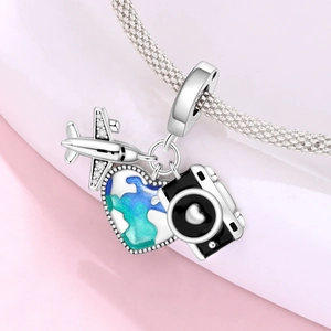Macro detail of silver airplane, camera and enamel earth charms on a mesh bracelet
