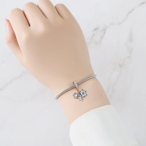 Pulsera de cadena de serpiente plateada con dije de copo de nieve azul y blanco en la muñeca